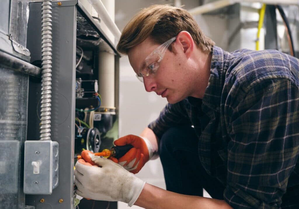 A repairman working inside a home, repairing a furnace.